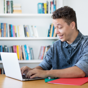 Smiling boy working at laptop in classroom