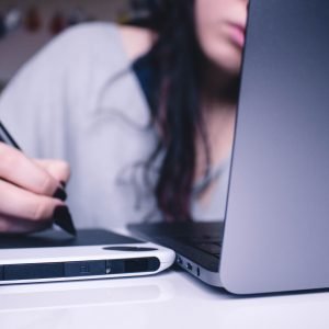 Back of open laptop with lady writing notes